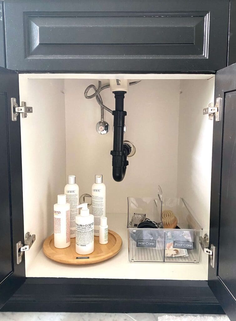 Sink plumbing and toiletry bottles inside cabinet