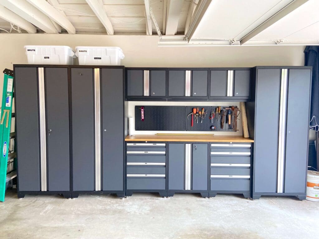 Organized garage with sleek black tool cabinets and a workbench.