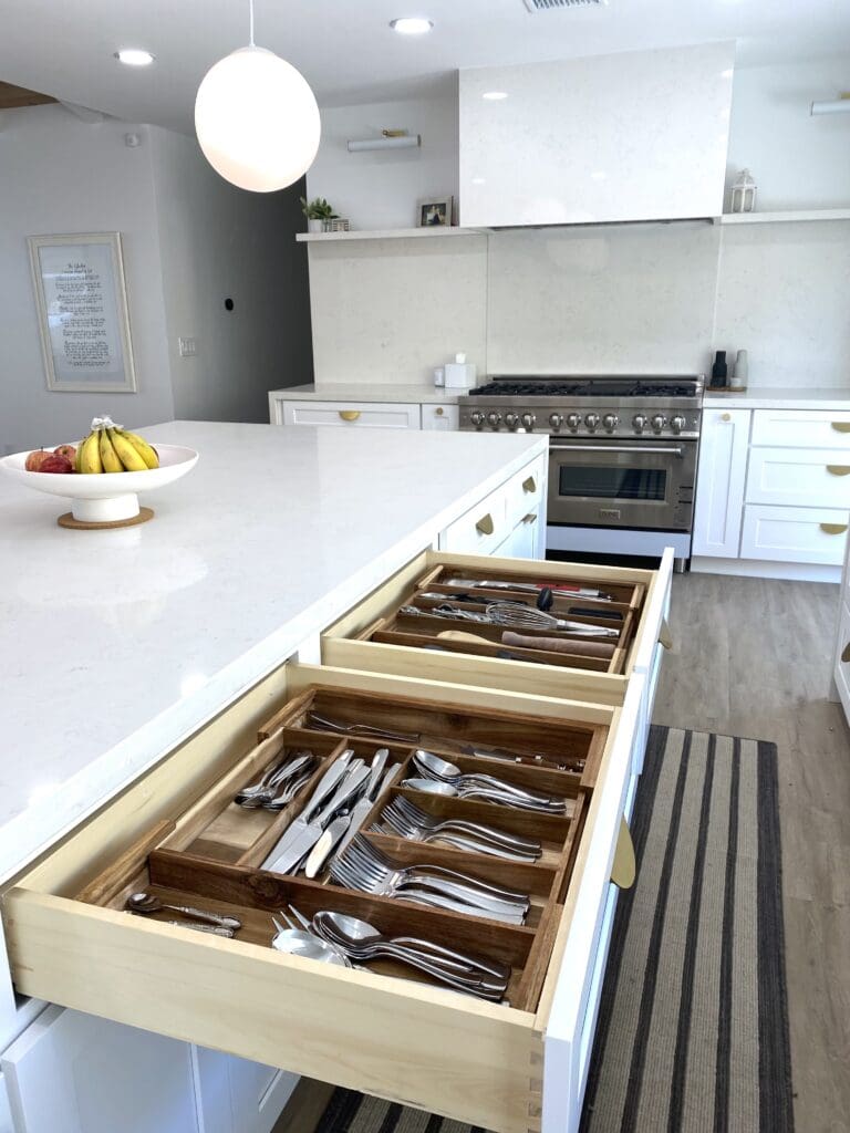 Organized kitchen drawers with neatly arranged cutlery in a modern white kitchen.