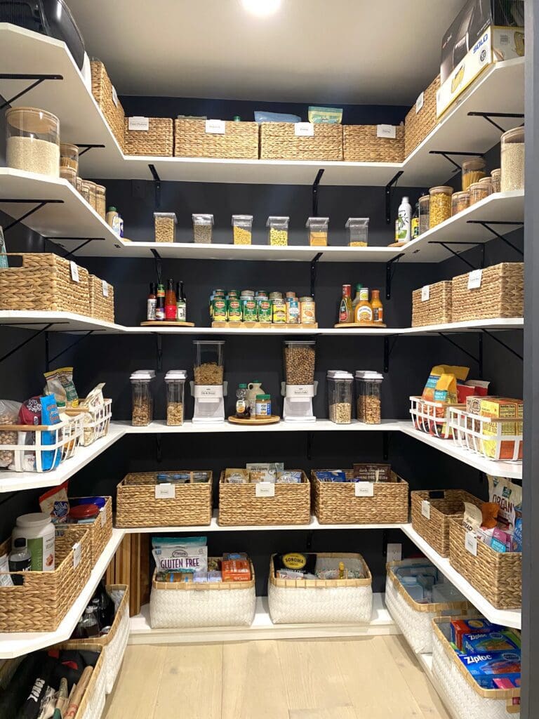 Organized pantry shelves with baskets and various food items.