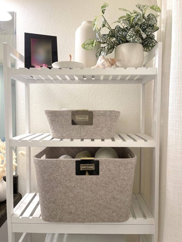 White shelving unit with two textured storage baskets and a plant on top.
