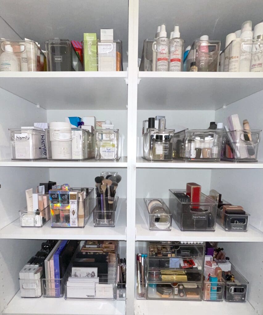 Organized makeup and skincare products neatly arranged on white shelves.