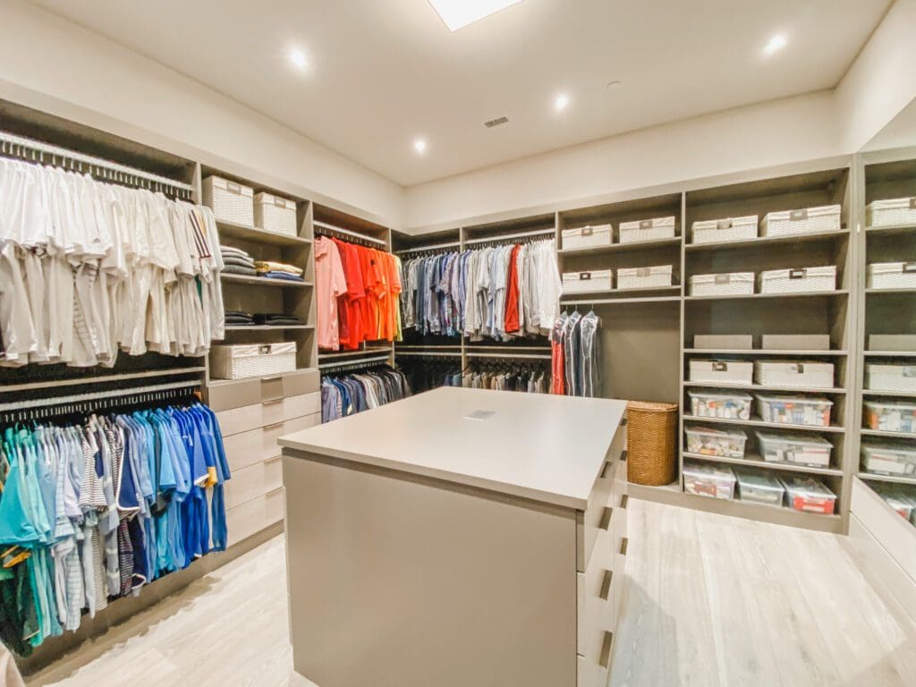 Organized spacious walk-in closet with clothing and shelves.