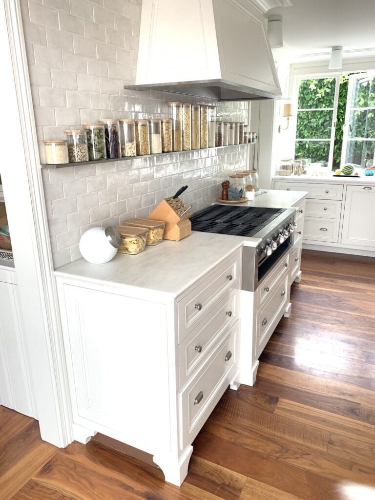 Bright modern kitchen with white cabinets and stainless steel stove.