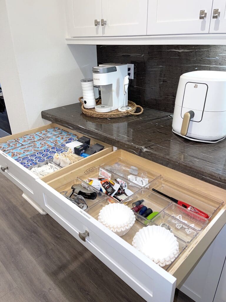 Organized drawer with coffee pods, stirrers, and supplies in a kitchen.