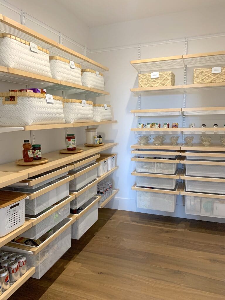 Organized pantry with labeled plastic bins on shelves.
