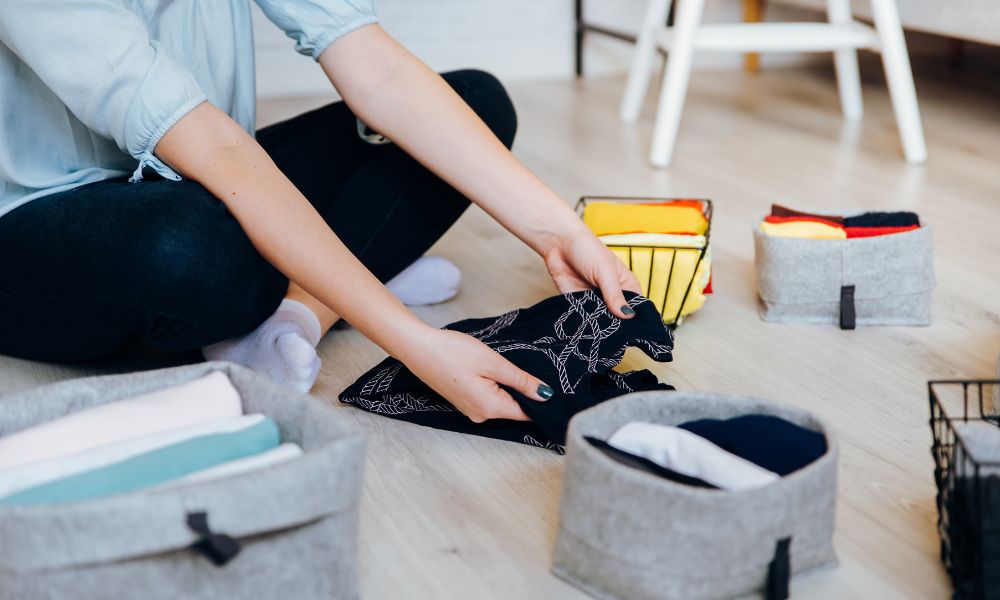 A Woman Folding a Shirt on the Floor