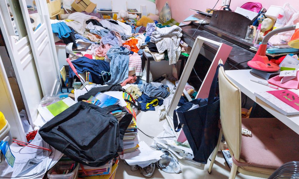 A Cluttered Space With Clothes and Books