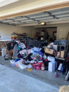Two car garage before decluttering, with a huge pile of household items, furniture and boxes