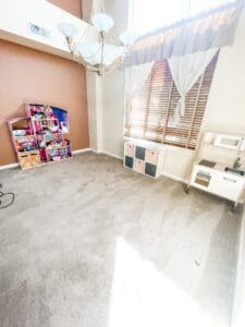 Same playroom after decluttering, with a clear tiled floor and a few toys neatly placed by the window