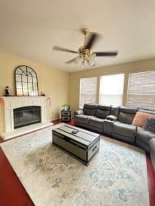 Family room after decluttering, with a clear rug, sectional sofa and fireplace in soft daylight