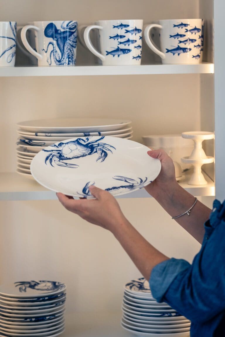 Organizer stacking blue and white plates on an open kitchen shelf