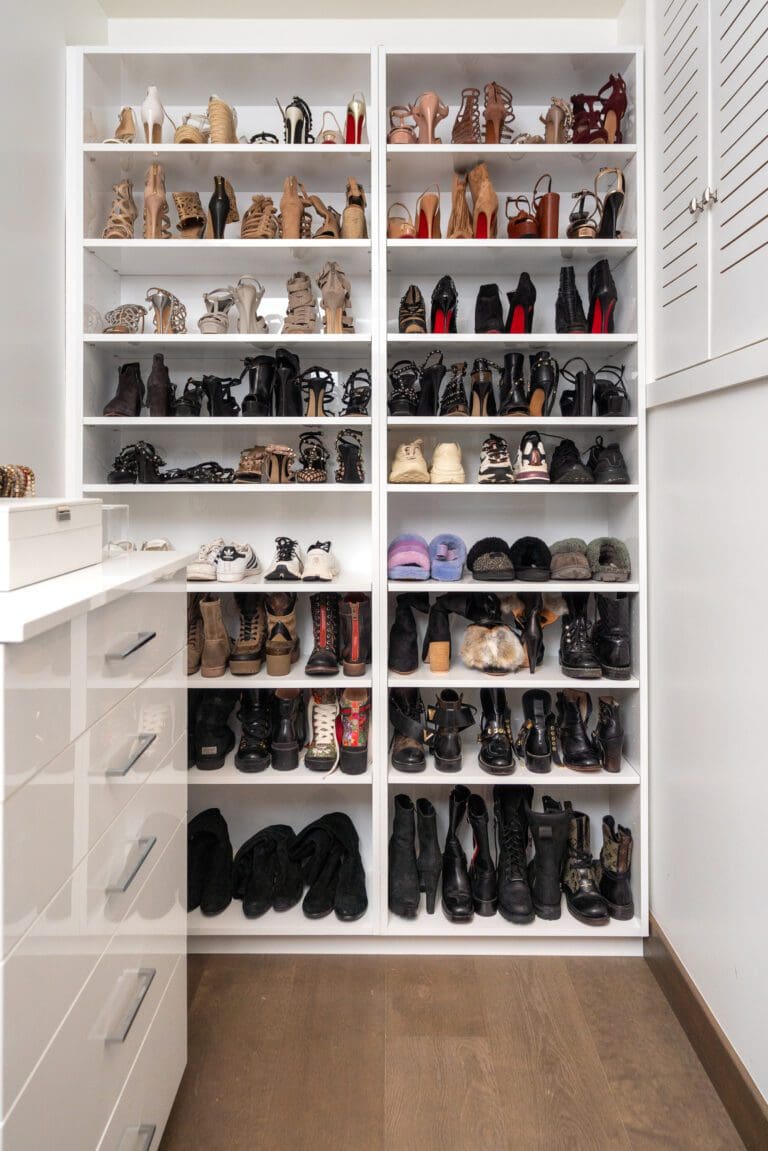 White built-in shoe shelves filled with heels, flats and sneakers