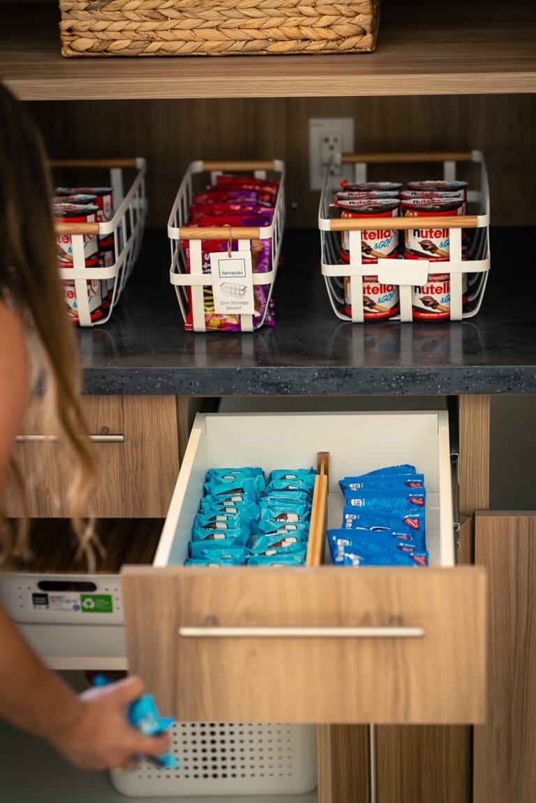 Office break room drawer with labeled clear bins of snacks and drinks