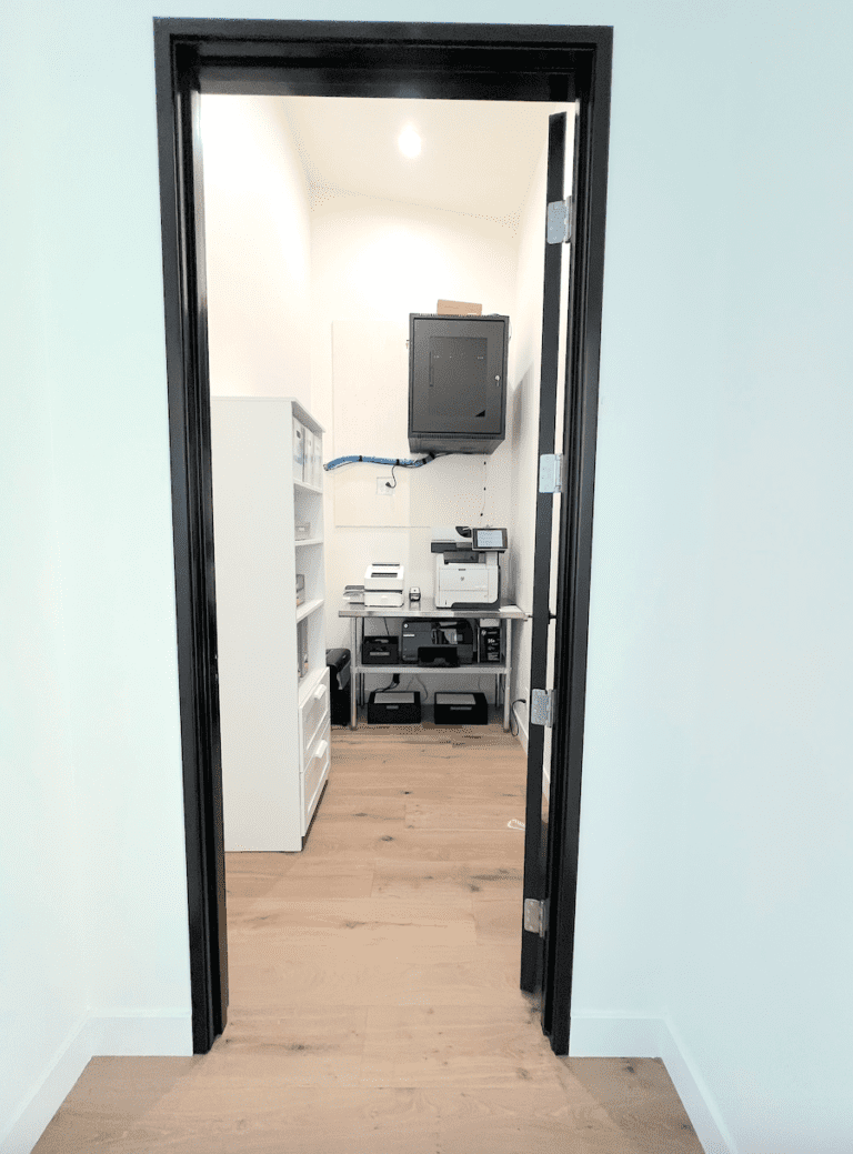 Office supply room after organizing, with white shelving and a clear printer station