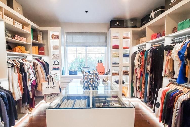 A walk in closet with lots of clothes and shoes