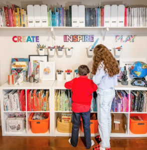 Two children standing in front of a bookcase full of books