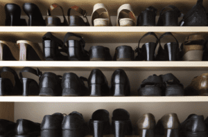 Many pairs of shoes on a shelf in a closet