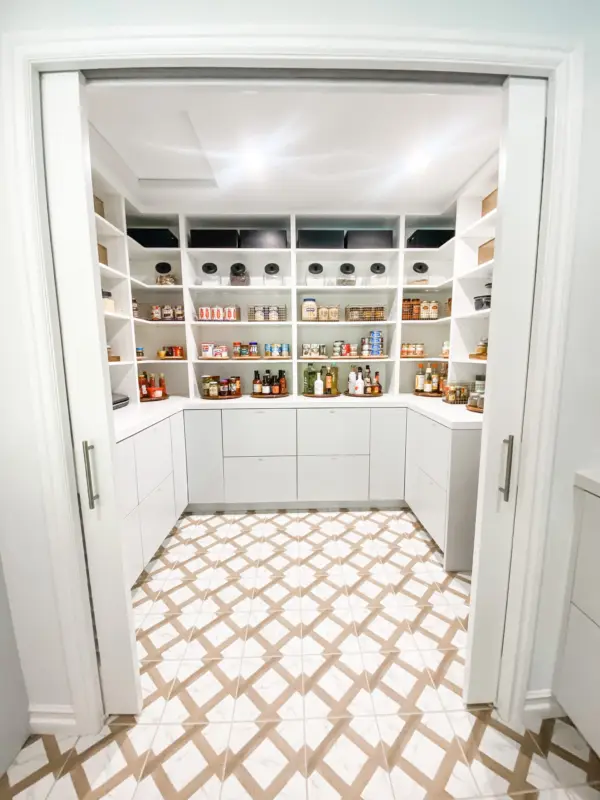 Walk-in pantry with white shelves, clear canisters and a patterned tile floor, organized by Simply Luxe
