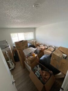 Guest room before unpacking, with moving boxes stacked across the floor under the window