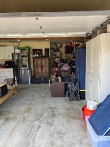 Two car garage after decluttering, with storage cabinets and belongings lined up along the walls