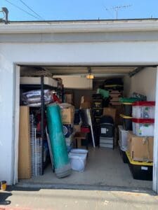 Garage before decluttering, with shelves, boxes and a rolled rug packed inside