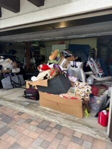 Two car garage before decluttering, filled with boxes, stuffed animals and stacked belongings