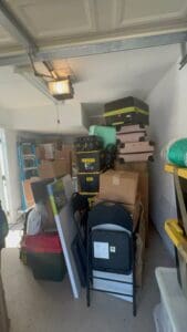 Garage before decluttering, with stacked boxes, suitcases and folding chairs