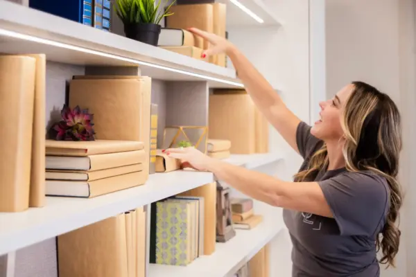 Simply Luxe founder Ryen Toft placing a book on an organized white shelf