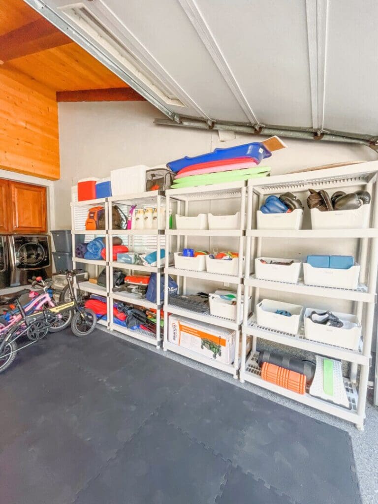 Organized garage shelves with colorful bins beside a home gym floor