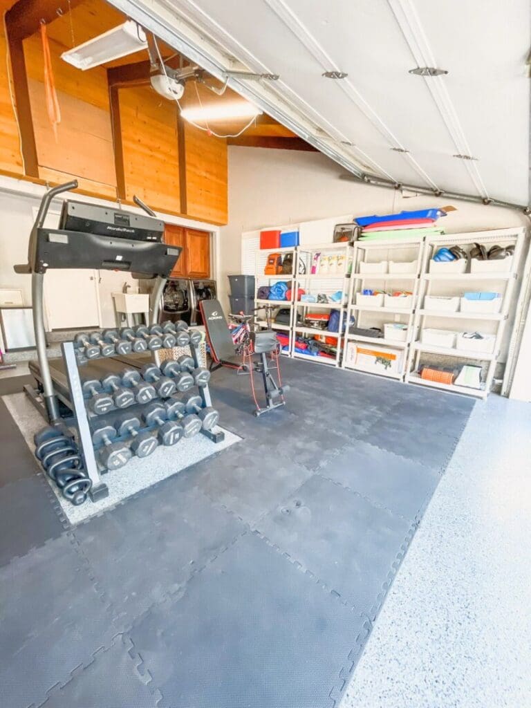 Garage gym corner with dumbbells and workout gear next to organized shelving