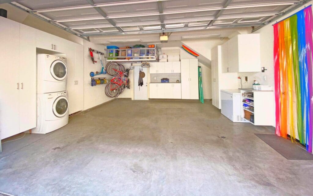 Clean two car garage with storage shelves, a washer and a dryer