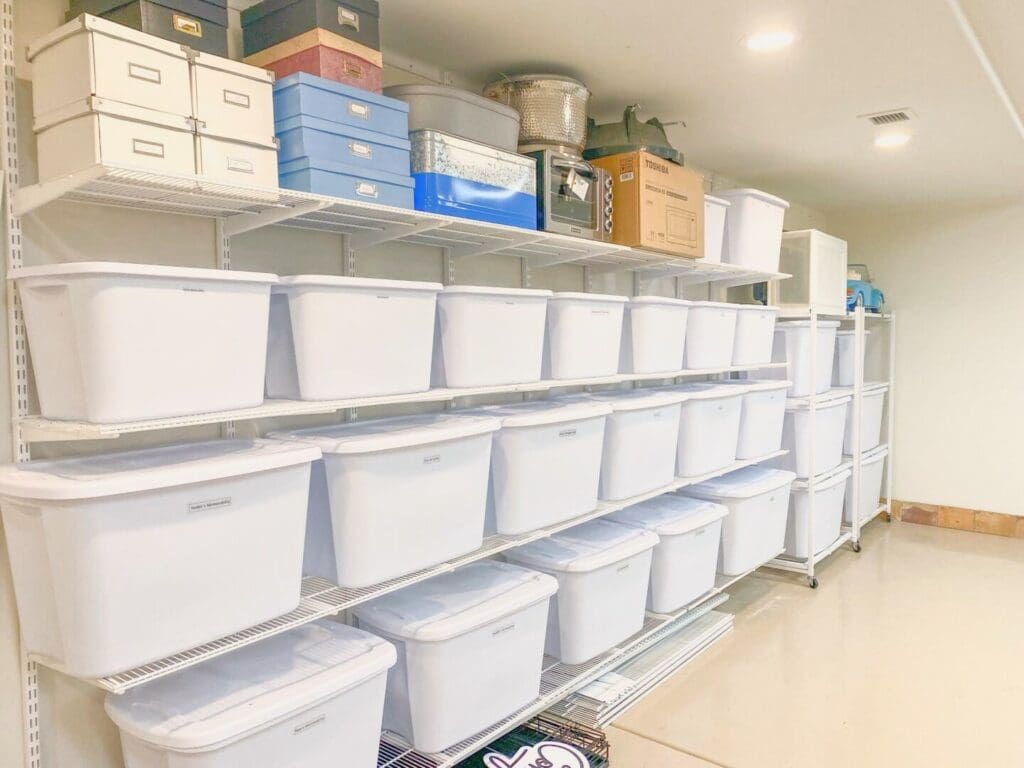 White storage bins stacked neatly along long garage shelves