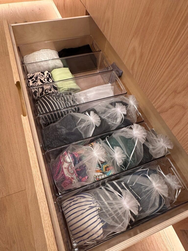 Closet drawer after organizing, with folded pieces and mesh bags in clear dividers, San Diego