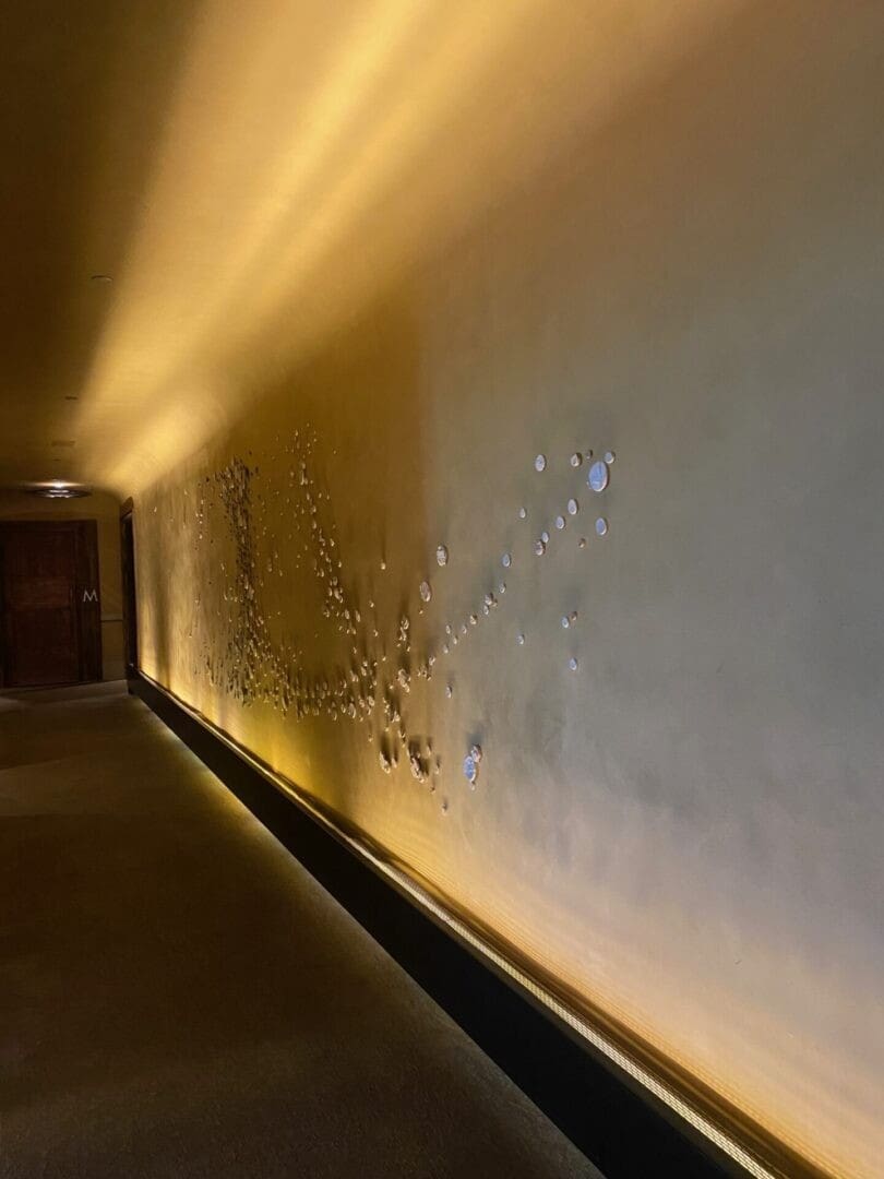 Dimly lit hallway with peeling wall paint and warm lighting.