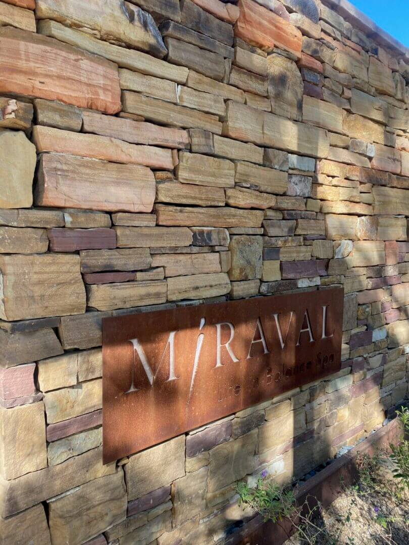 Stone wall with a rusty metal plaque displaying faded writing.