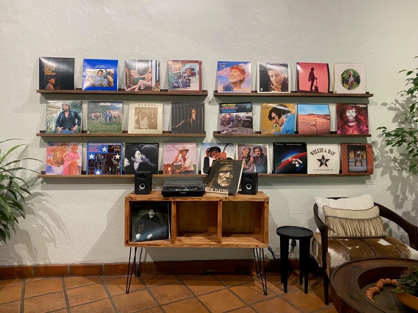 A wall displaying a collection of vinyl records above wooden shelves with audio equipment.
