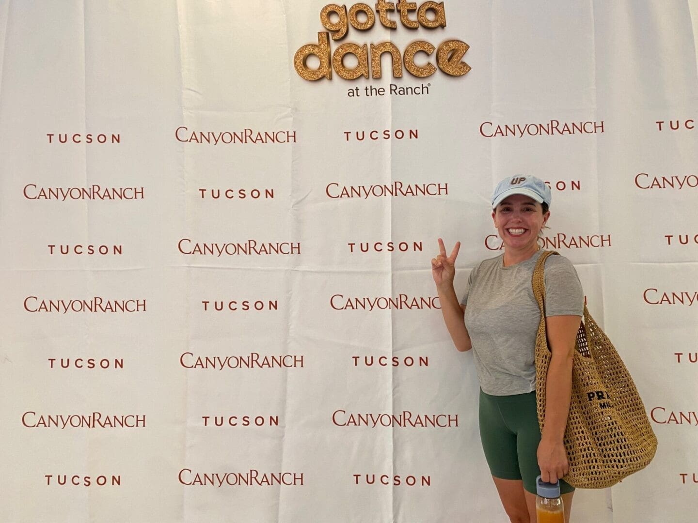 Woman posing with a peace sign at a Tucson dance event backdrop.