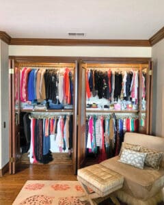 Double closet after the Simply Luxe unpack, clothes hung by color with a reading chair in front, Newport Beach
