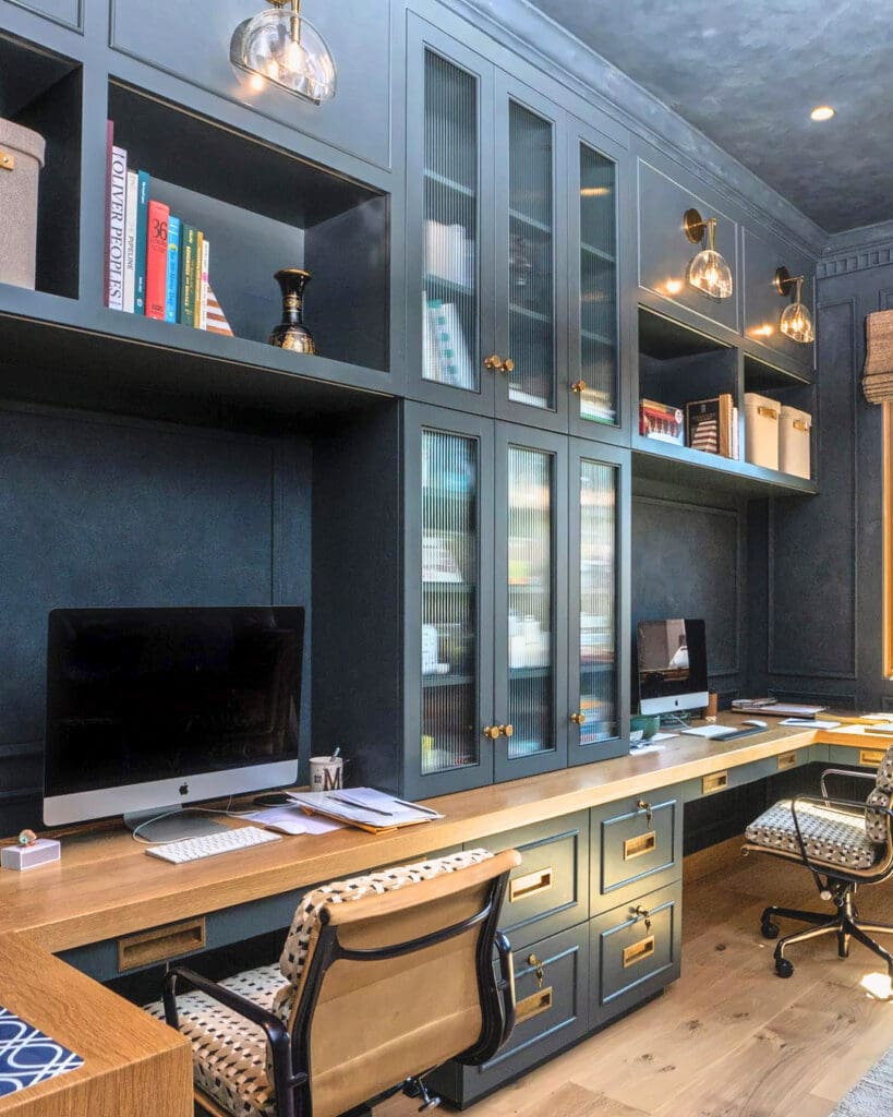 Same blue home office after Simply Luxe styling, with dual desks, gold sconces lit and shelves neatly set, San Diego