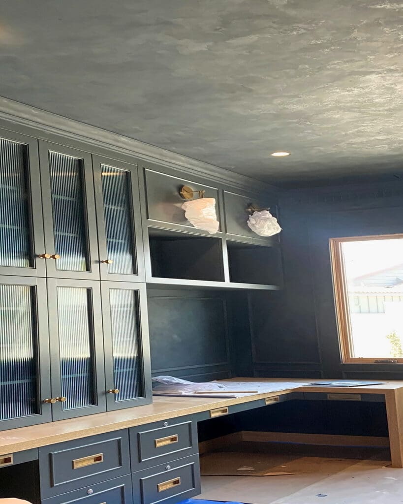 Home office during the blue cabinetry build-out, with protective floor cover and sconces still wrapped, San Diego
