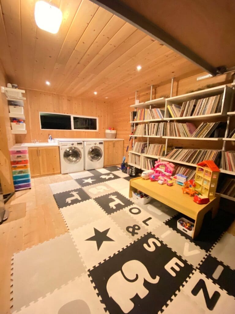Same bonus room after decluttering, set up as a playroom with a foam mat floor, a kids table and organized bookshelves