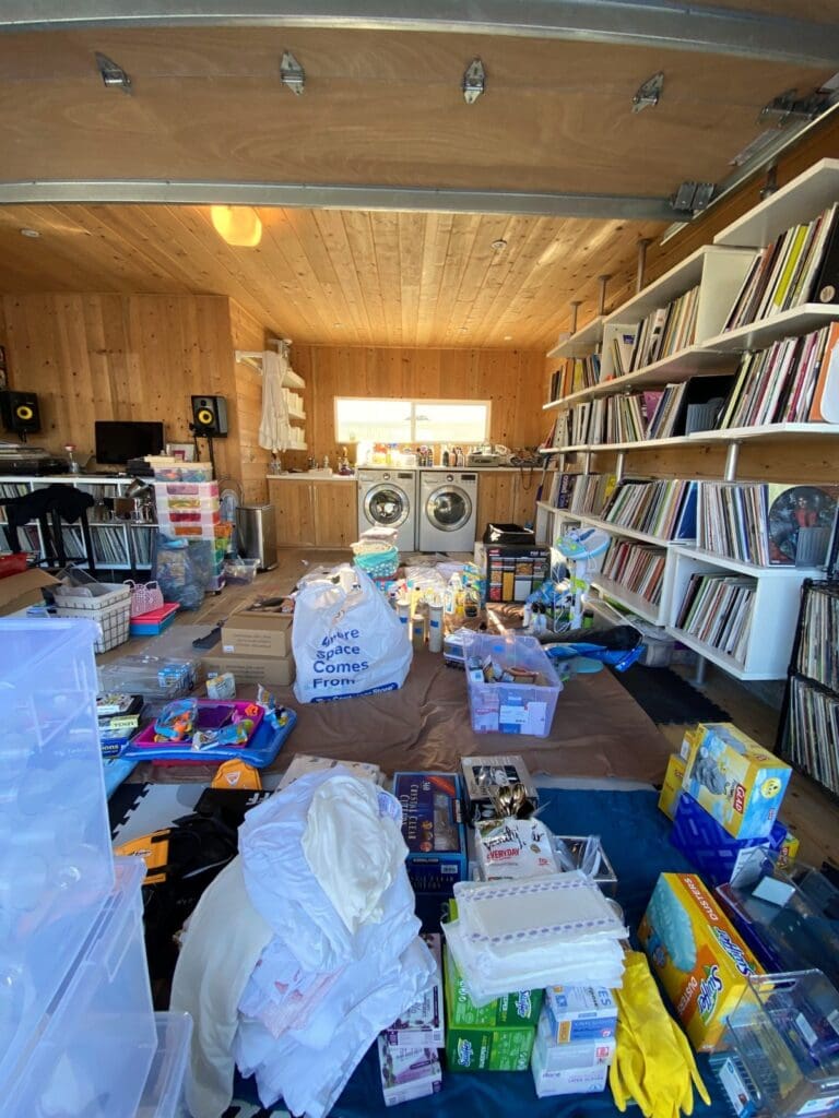 Bonus room before decluttering, with bags, bins and toys covering the floor