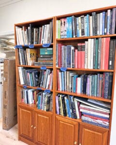 Wood bookcase after unpacking, with books grouped by color and size, San Diego home