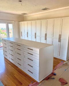 California Closets build-out going in: white drawer island and wall of wardrobe cabinets, San Diego