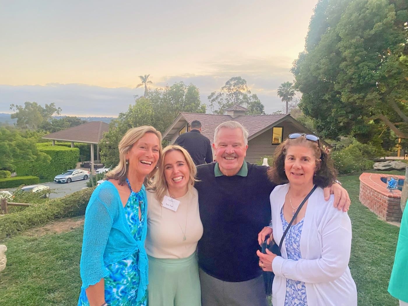 Ryen Toft smiling with three fellow supporters on a lawn at sunset during a Clearity Foundation evening