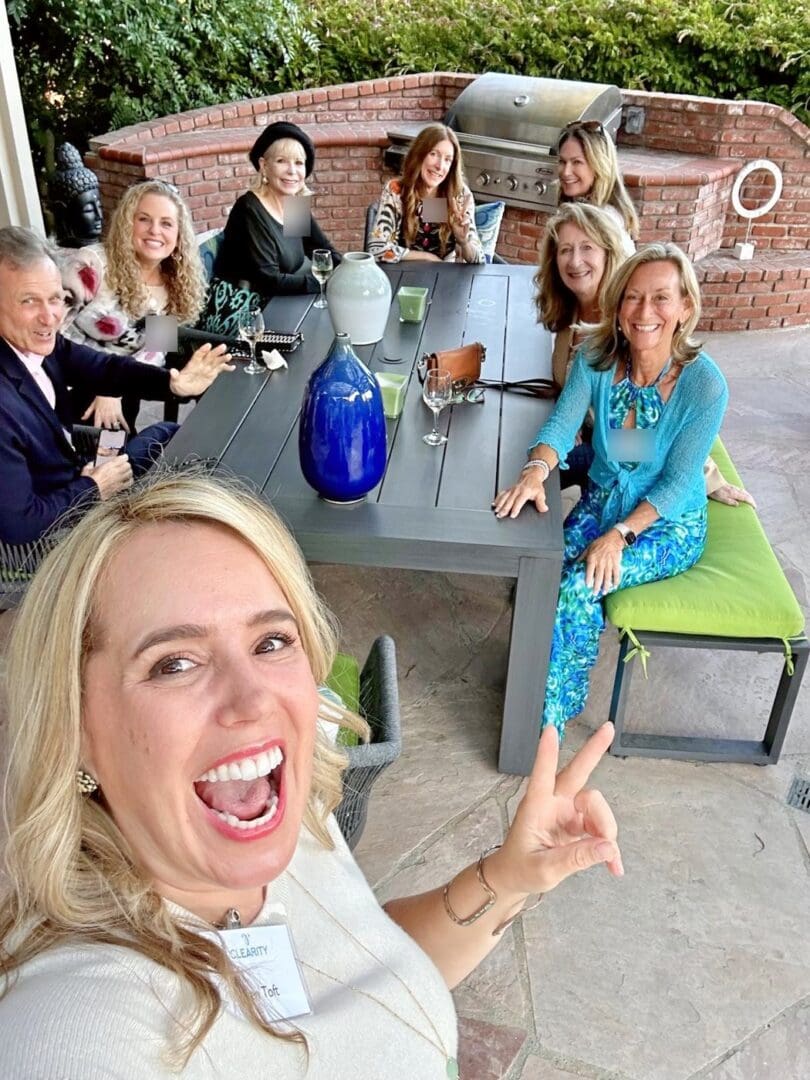 Ryen Toft taking a smiling selfie with fellow supporters around an outdoor dinner table at a Clearity Foundation gathering