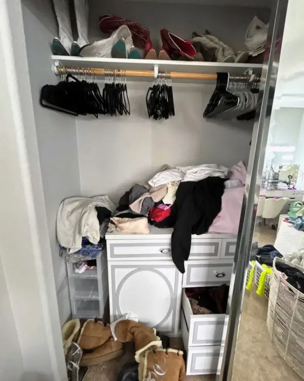 Reach-in bedroom closet before organizing, with piled clothes, empty hangers and shoes on the floor, Orange County home