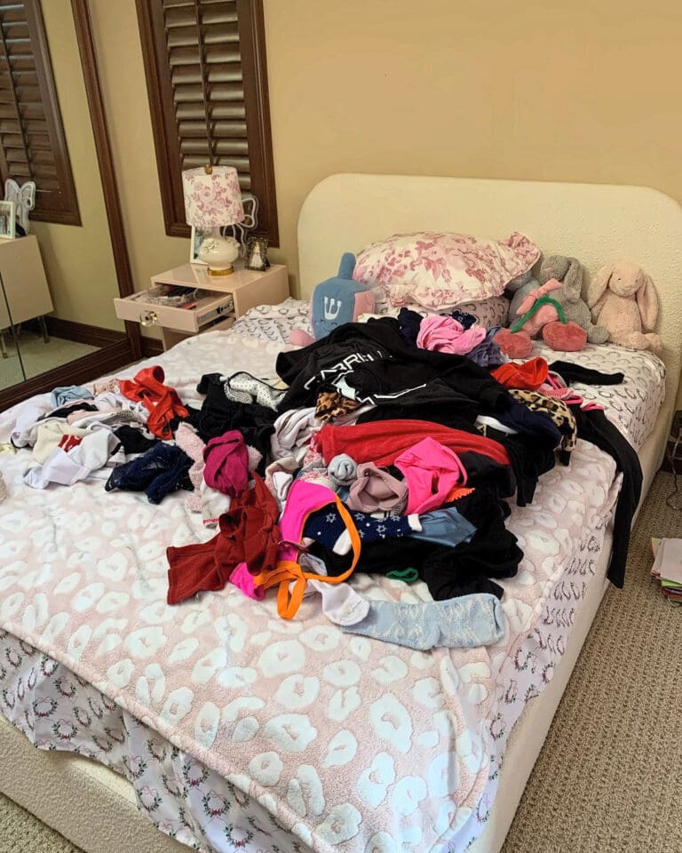 Bed piled with clothes before closet editing and packing, Newport Beach