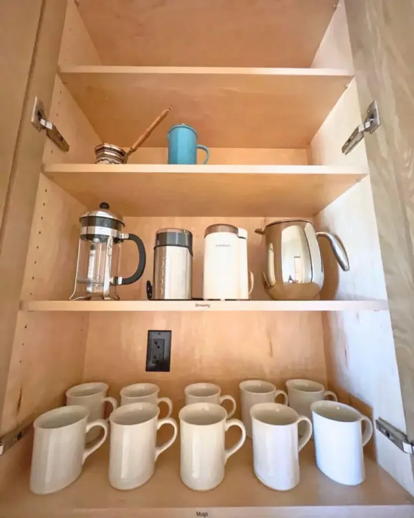 Coffee station after unpacking, with white mugs lined up below a French press and kettles